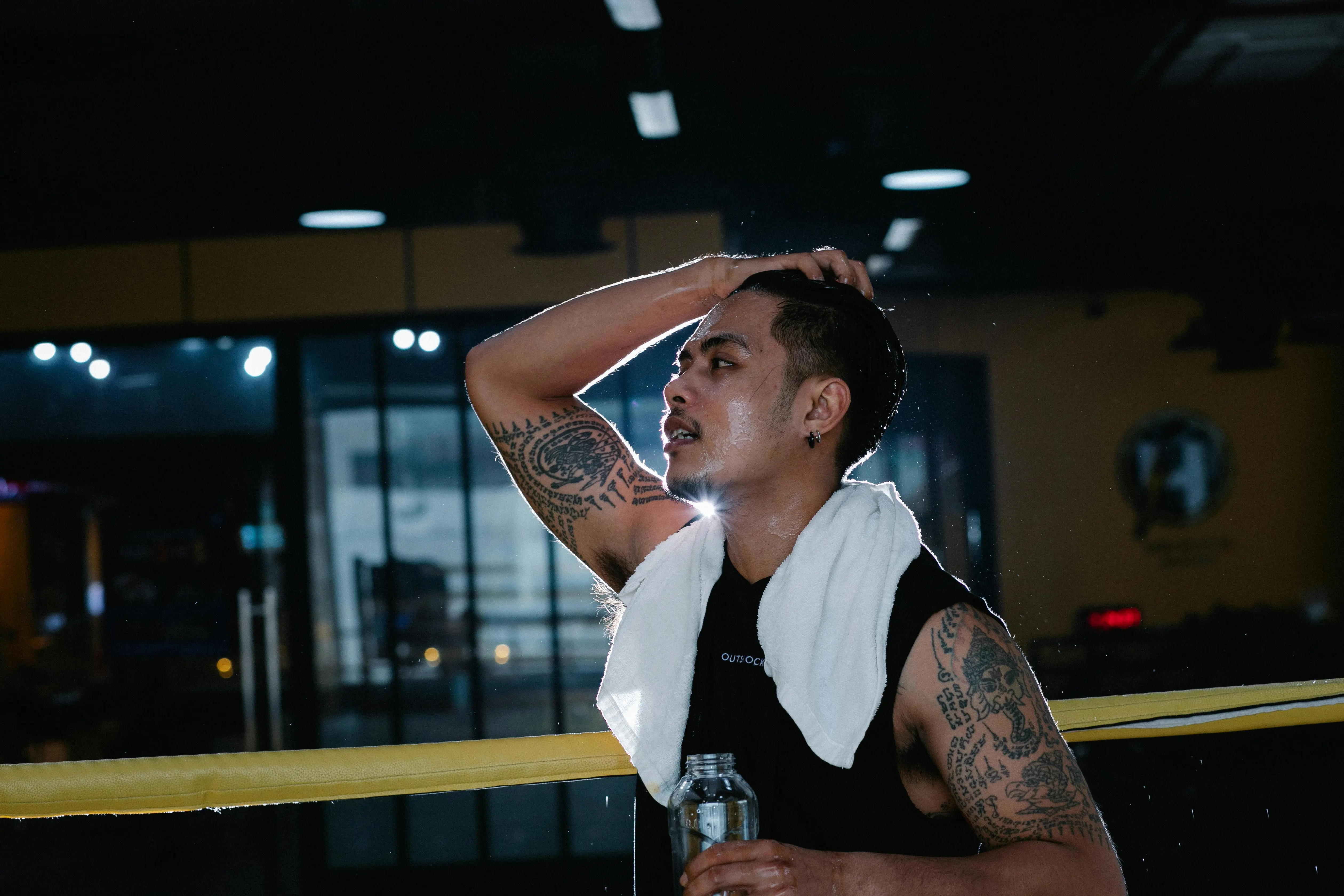 A tattooed man standing confidently in a boxing ring